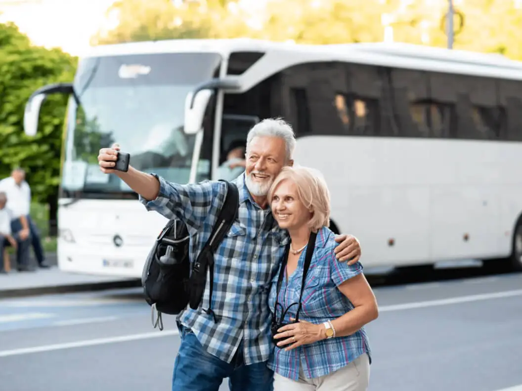 Happy couple taking a selfie standing front of bus